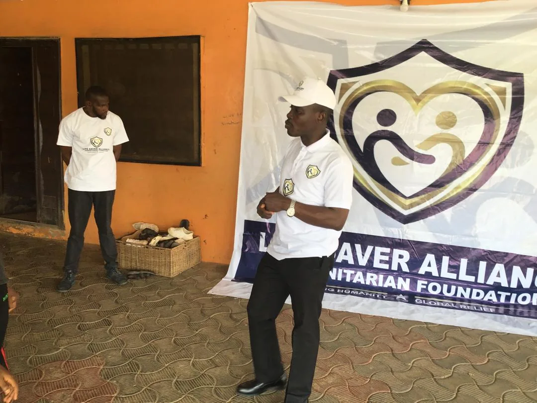 An LAHF volunteer speaks with children beside the foundation banner at City of Refuge Orphanage