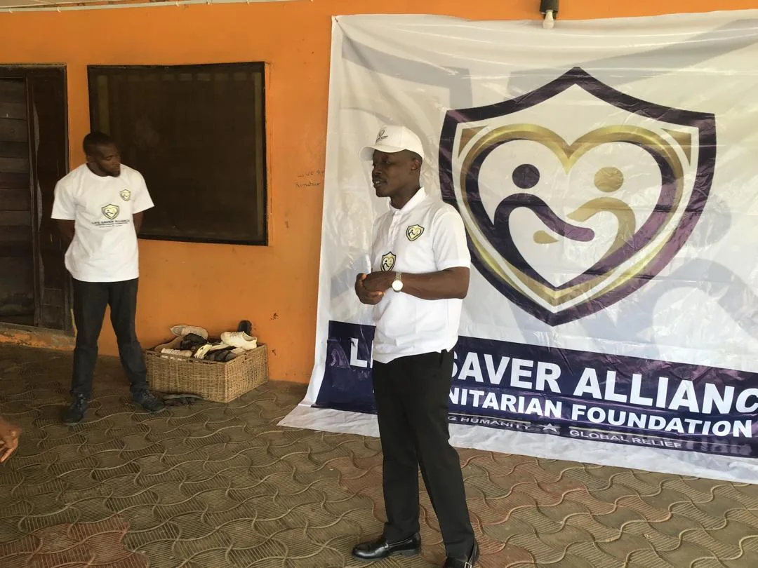 An LAHF volunteer speaks with children beside the foundation banner at City of Refuge Orphanage
